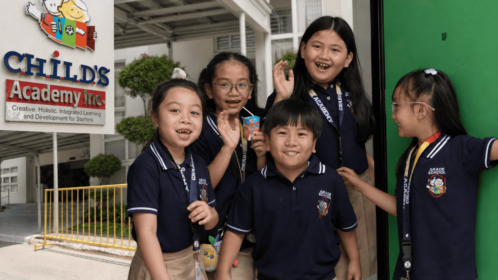 Smiling CHILD’S Academy students in uniform gathered outside their school, with the campus entrance and academy signage visible.